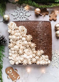 a chocolate cake decorated with white icing and christmas decorations next to gingerbreads