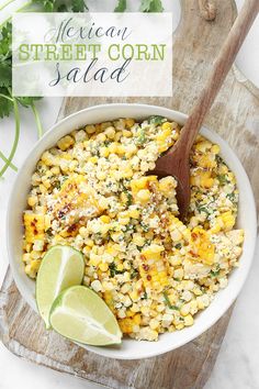 mexican street corn salad in a white bowl with lime wedges and cilantro