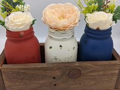 three painted jars with flowers in them