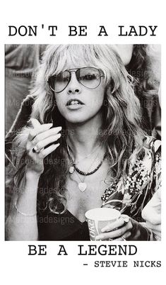 a black and white photo of a woman with glasses holding a cup in her hand