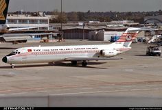 an airplane is parked on the tarmac near other planes and airport buildings in the background