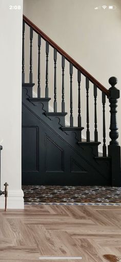 an empty room with wooden floors and black railings on the stairs, next to a fire hydrant