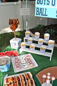 a table topped with lots of hot dogs and cupcakes