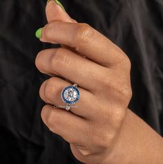 a woman's hand holding a ring with a blue and white design on it