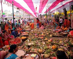 many people are gathered around baskets full of fruits and vegetables on the ground in front of tents