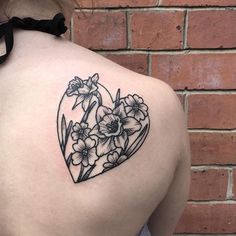 a woman's back with flowers in the shape of a heart on her left shoulder