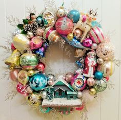 a christmas wreath with ornaments hanging on the wall and a birdhouse in the center