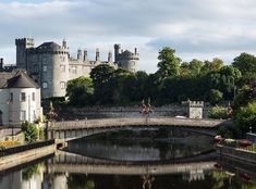 a bridge over a body of water with buildings in the background and trees on either side