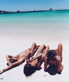 two women laying on the beach in bikinis