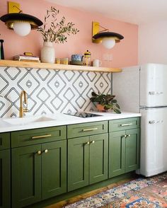 a kitchen with green cabinetry and white refrigerator freezer next to a rug on the floor