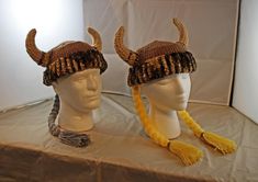 two knitted hats with horns and tassels on top of a white table