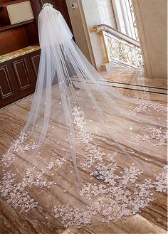 a wedding veil with pink flowers on the bottom is shown in front of a doorway