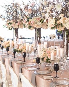 the tables are set with white and pink flowers in vases, candles and wine glasses