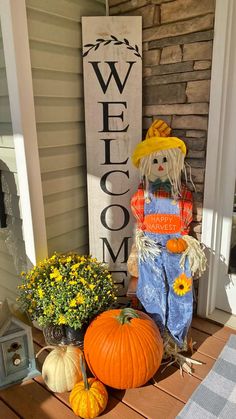 a scarecrow sitting on the front porch next to pumpkins