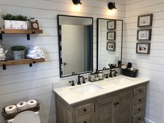 a bathroom with two sinks, mirrors and toiletries on the wall above it is decorated in wood planks