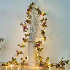 a vase filled with flowers sitting on top of a wooden table next to some lights