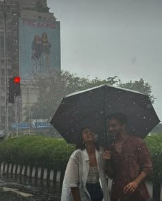 two people standing under an umbrella in the rain