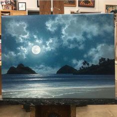 an easel with a painting on it that has a full moon in the sky