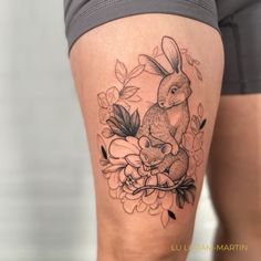 a woman's thigh with a tattoo of a rabbit and flowers on the side