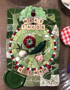 a mosaic plate with words made to look like food and vegetables on it next to utensils