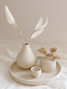 two white vases sitting on top of a plate