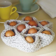 some eggs are in a basket on a table next to a cup and saucer