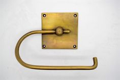 an antique brass towel ring on a white wall, with the handle slightly bent down