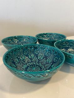 four blue bowls sitting on top of a white counter next to an empty glass container