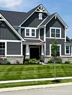 a large gray house with lots of windows and green grass in front of the house