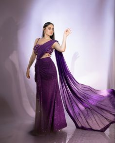 a woman in a purple sari is posing for the camera with her hand on her hip