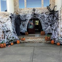 halloween decorations on the front steps of a house with spider webs and pumpkins