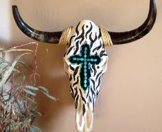 a cow skull with a cross painted on it's face next to a potted plant