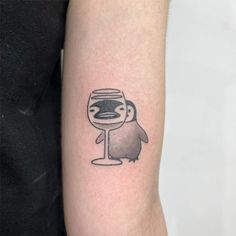 a penguin with a wine glass tattoo on the arm