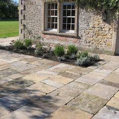 an outdoor patio with stone pavers and plants in the foreground, next to a brick building