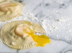 two small pastries on a table covered in powdered sugar and yellow liquid with a spoon