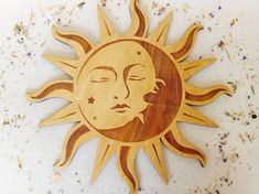 a wooden sun with a face on it next to dried lavenders and flowers in the background