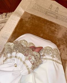 a small baby in a white outfit laying on the floor next to a wooden box