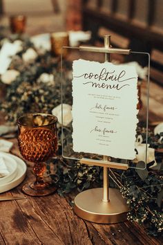 a wooden table topped with plates and glasses filled with food next to a sign that says cocktail menu