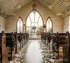 the aisle is decorated with white flowers and greenery as well as wooden pews