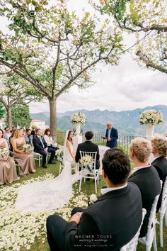 a couple getting married in front of an outdoor wedding ceremony at the top of a hill