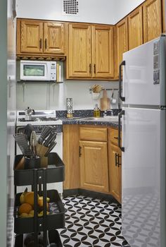 a kitchen with wooden cabinets and black and white tile flooring on the floor is shown