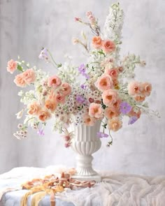 a white vase filled with lots of flowers on top of a table