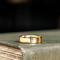 a gold wedding band sitting on top of an old book