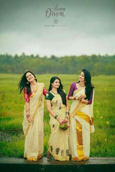 three beautiful women standing next to each other in front of a green grass covered field