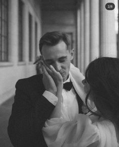 a man in a tuxedo is holding his head to his face