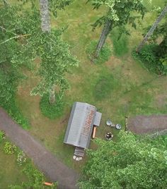 an aerial view of a small cabin in the middle of some trees and dirt roads