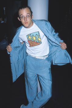 a man in blue pants and a white t - shirt is holding his jacket open