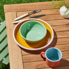 two bowls on a wooden table with utensils