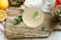 a close up of a drink in a glass on a table with lemons and mint