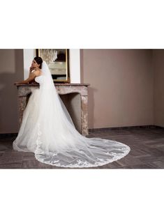 a woman in a wedding dress standing next to a fireplace